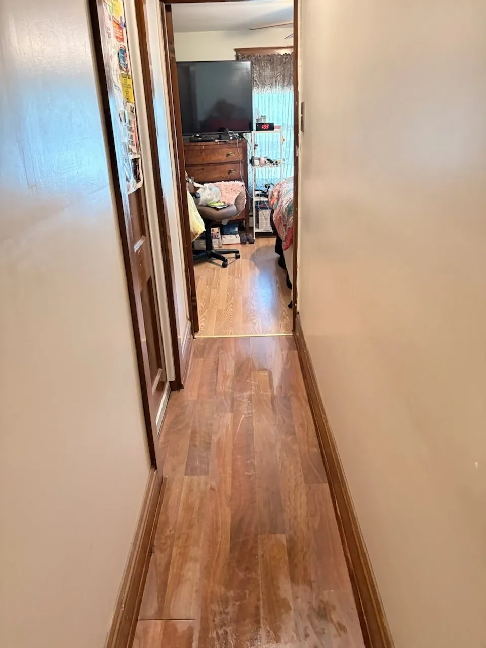 Mopped hardwood-look floors and a clean hallway leading into a bedroom