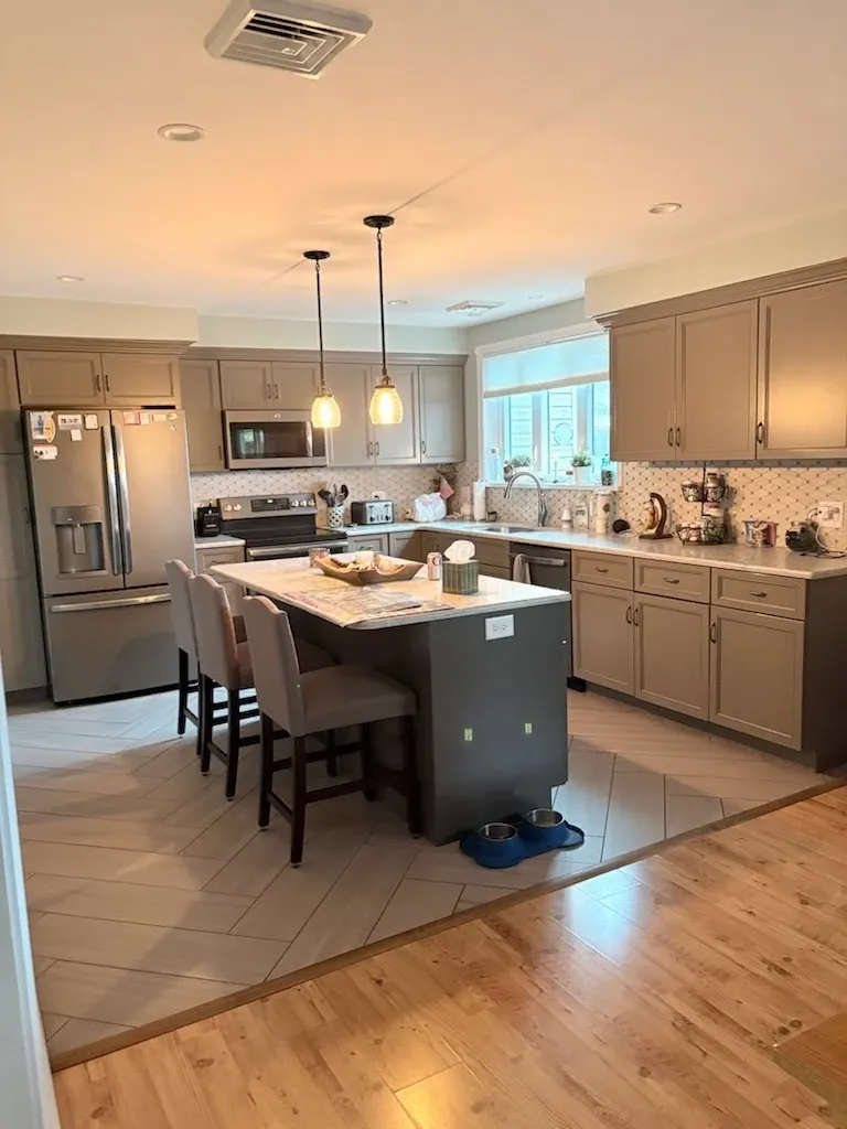 Freshly cleaned kitchen with island, gray cabinets, and herringbone tile floor in a Berks County home